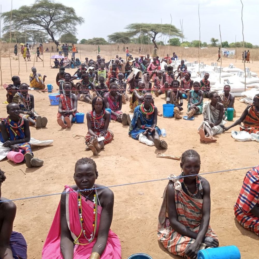 Beneficiaries in Kapoeta North County waiting in order and observing social distance to recieve their food entitlements from ADRA. Funding by WFP.